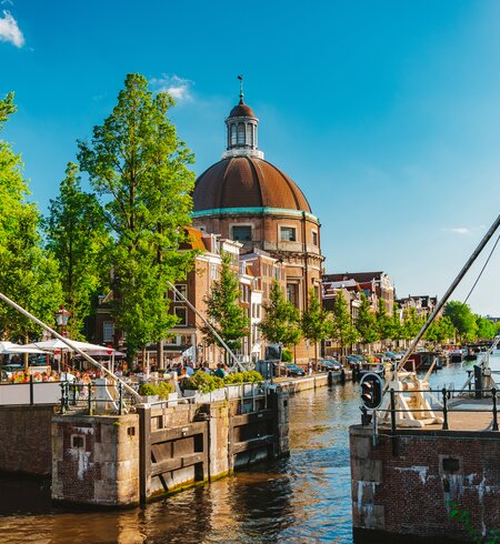 Grachtenschleuse mit belebtem Café und der klassizistisch barocken Ronde Lutherse Kerk im Hintergrund | © Gettyimages.com/Rocky89