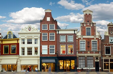 Stadtszene Amsterdam mit liebevoll restaurierten Giebelhäusern und kleinen Ladengeschaeften an einer Grachtenbruecke | © Gettyimages.com/MediaProduction