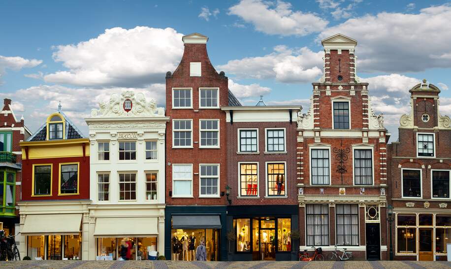 Stadtszene Amsterdam mit liebevoll restaurierten Giebelhäusern und kleinen Ladengeschaeften an einer Grachtenbruecke | © Gettyimages.com/MediaProduction
