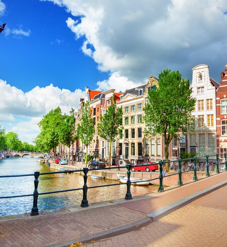 Blick auf die Amstel und eine Bruecke mit einer historischen Strassenlaterne im linken Vordegrund | © Gettyimages.com/adisa