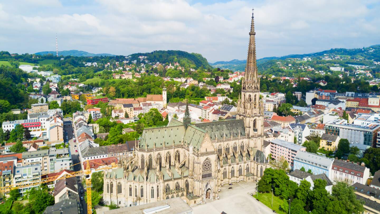 Blick von oben auf die Marienkirche in Linz mit wunderschoener Landschaft | © Gettyimages.com/saiko3p