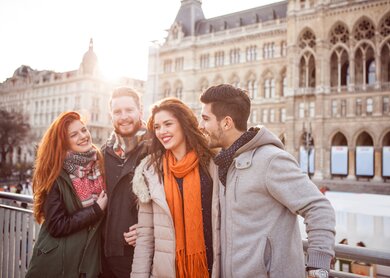 Freunde, die im Winter im Freien in Wien stehen und warme Kleidung tragen | © Gettyimages.com/svetikd