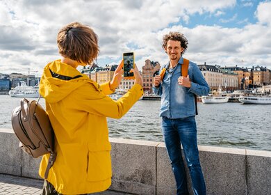 Freundin macht ein Foto von ihrem Freund am Kai in Stockholm, Schweden | © urbazon