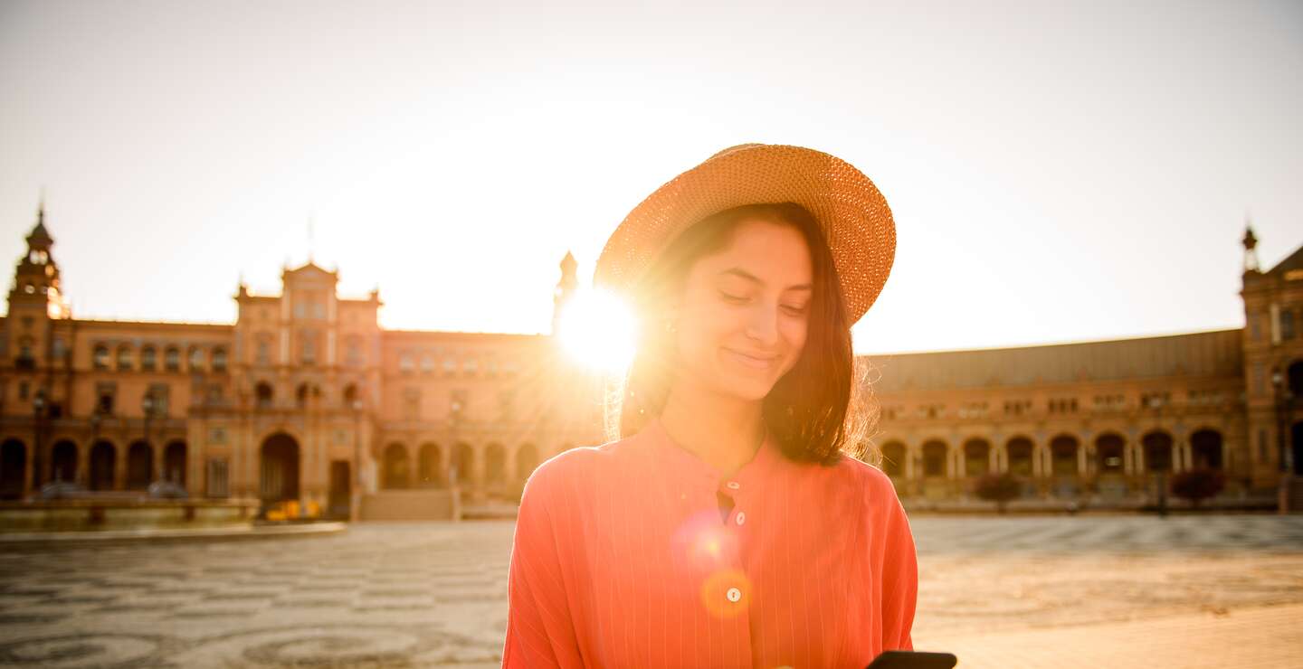 Elegante Frau beim Besuch der Plaza de Espana, Sevilla mit Handy in der Hand | © gettyimages.com/MStudioimages