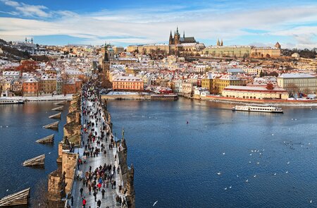 Auf der Karlsbrücke in Prag laufen Touristen im Winter. Im Hintergrund ist das Viertel Mala Strana und die Prager Burg.  | © Gettyimages.com/rusm