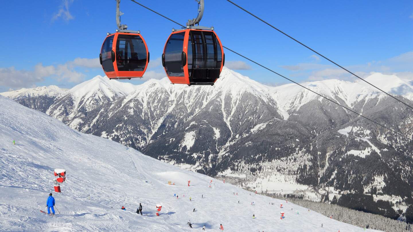 Skilift im Skigebiet Bad Gastein, umgeben von schneebedeckten Gipfeln der Hohen Tauern Alpen, unter klarem Winterhimmel. | © Gettyimages.com/tupungato