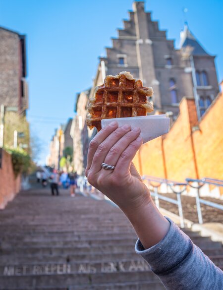 Belgische Waffel vor dem verschwommenen Hintergund der Montagne de Bueren Treppe in Lüttich | © gettyimages.com/MilosRuzicka