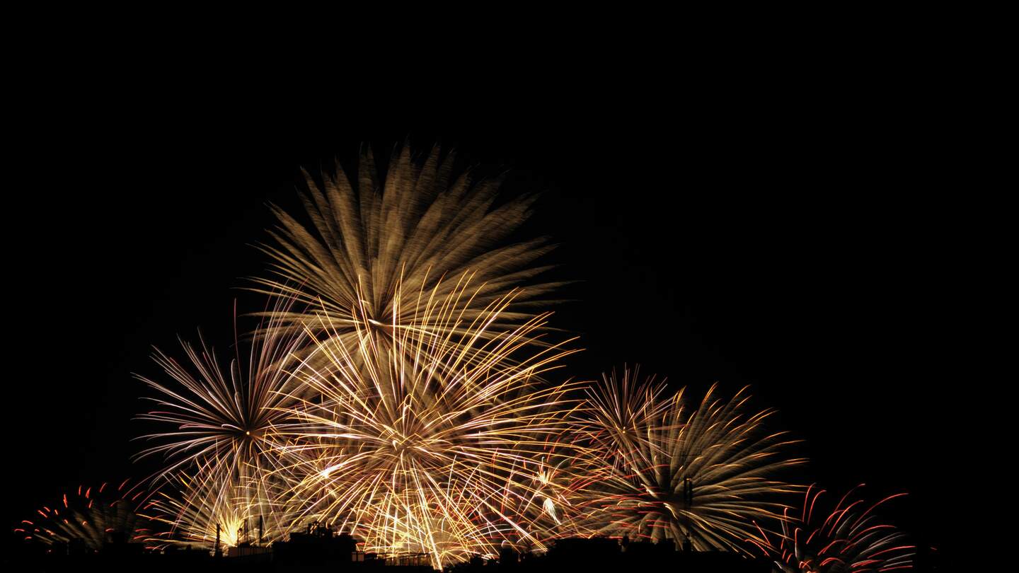 Feuerwerk explodiert vor einem schwarzen Himmel, über den Dächern von Antibes Juan-les-Pins. Tag der Bastille, 14. Juli. | © Gettyimages.com/christopherames