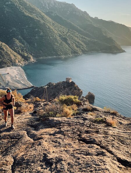 Junge Frau laeuft am Morgen den Berghang ueber dem Meer hinauf  | © Gettyimages.com/ascentxmedia