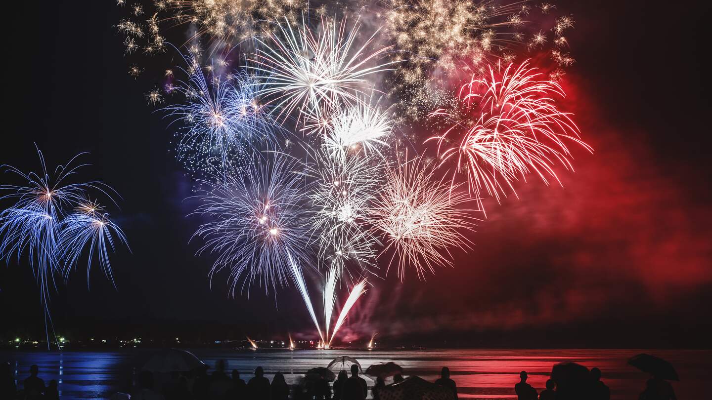 Schoene blaue, weisse und rote Feuerwerk Pyrotechnik wie, franzoesische Flagge Farben mit unkenntlich Menge Silhouetten beobachten | © Gettyimages.com/gregory_dubus