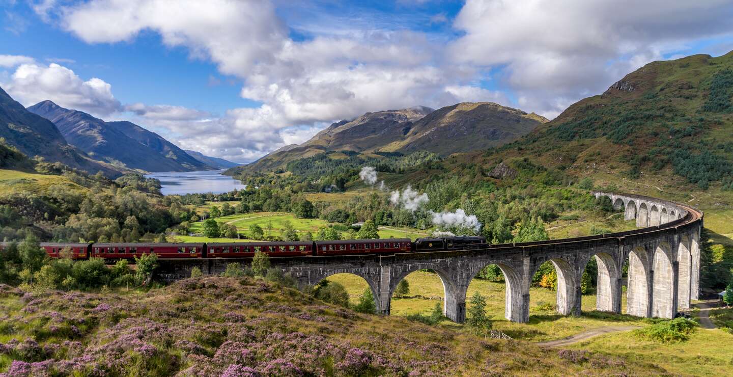 Berühmten Glenfinnan Eisenbahnviadukt in Schottland. Ein Zug fährt gerade über das gigantische Bauwerk mit atemberaubenden Hintergrund | © Gettyimages:com/catuncia