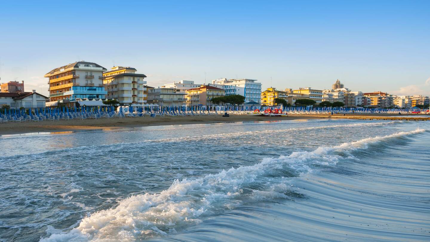 Strand von Lido di Jesolo vom Meer aus betrachtet mit Sonnenschirmen und Liegen und der Hotelpromenade im HIntergrund | © Gettyimages.com/Maximastudio
