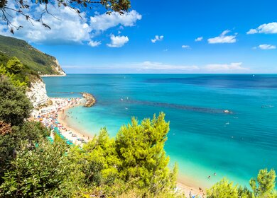 Tagesansicht des beruehmten Strandes voller Touristen in Sirolo, Italien | © Gettyimages.com/eddygaleotti