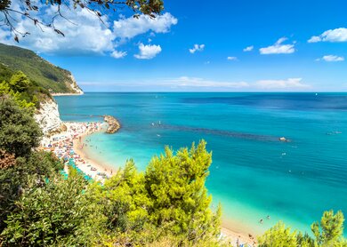 Tagesansicht des beruehmten Strandes voller Touristen in Sirolo, Italien | © Gettyimages.com/eddygaleotti