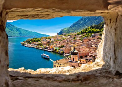 Blick durch Steinfester auf Limone sul Garda am Gardasee mit ablegendem Schiff | © Gettyimages.com/xbrchx