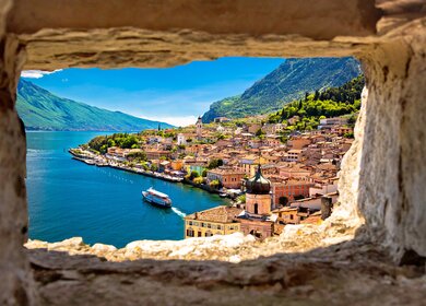 Blick durch Steinfester auf Limone sul Garda am Gardasee mit ablegendem Schiff | © Gettyimages.com/xbrchx