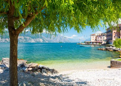 Auf dem Bild sieht man den See mit den felsigen Bergen im Hintergrund. Ein Baum ragt von links in das Bild | © Gettyimages.com/milenapigdanowicz-fidera