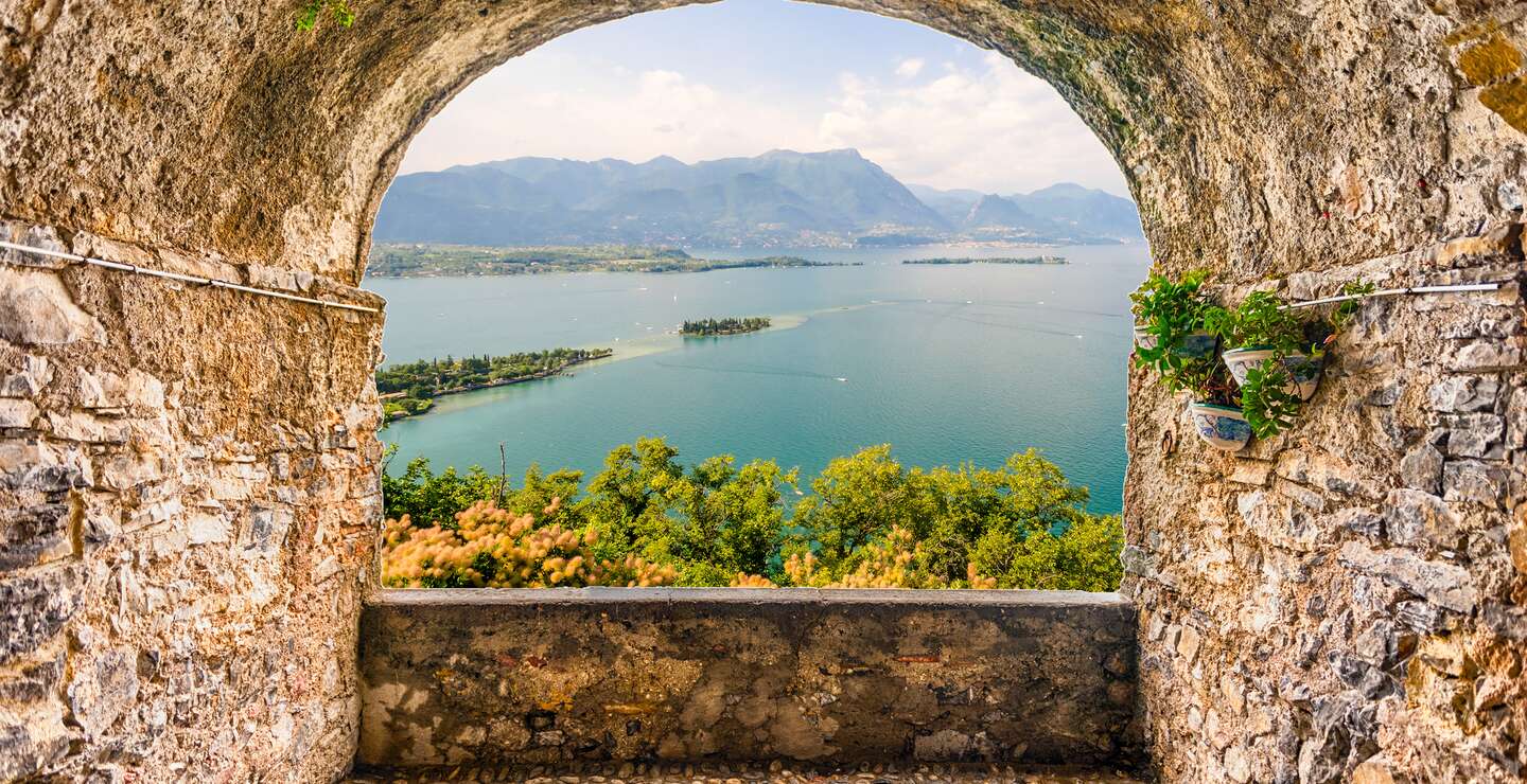 Blick von einem Felsbalkon auf den Gardasee und Berge im Hintergrund | © © Gettyimages.com/bwzenith