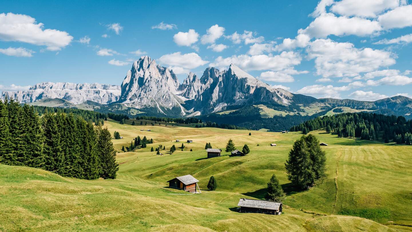 Aussicht auf die Seiser Alm mit Schutzhuetten in Suedtirol bei Sonnenschein und leichter Bewoelkung | © Gettyimages.com/FilippoBacci