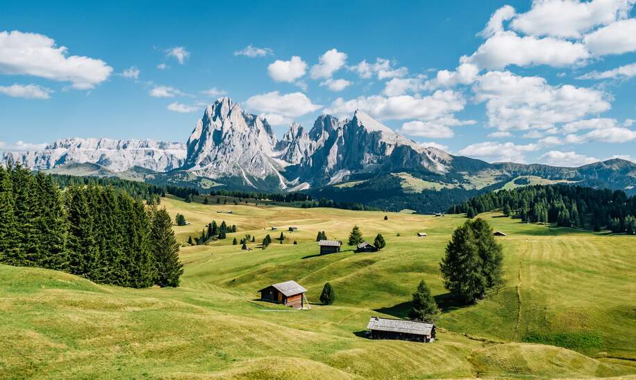 Aussicht auf die Seiser Alm mit Schutzhuetten in Suedtirol bei Sonnenschein und leichter Bewoelkung | © Gettyimages.com/FilippoBacci