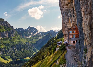 Ein Haus ist an einen Felsen gebaut worden. Links geht es steil bergab. | © Gettyimages.com/rusm