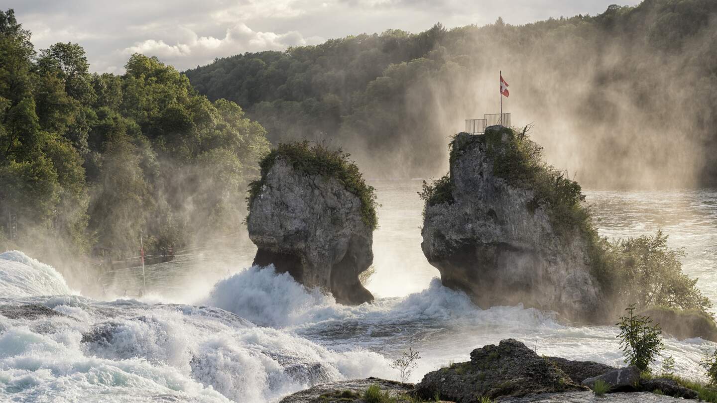 Man sieht den tosenden Fluss den Wasserfall runter strömen. In der Mitte befinden sich zwei Felsen. | © Gettyimages.com/kontrast-fotodesign