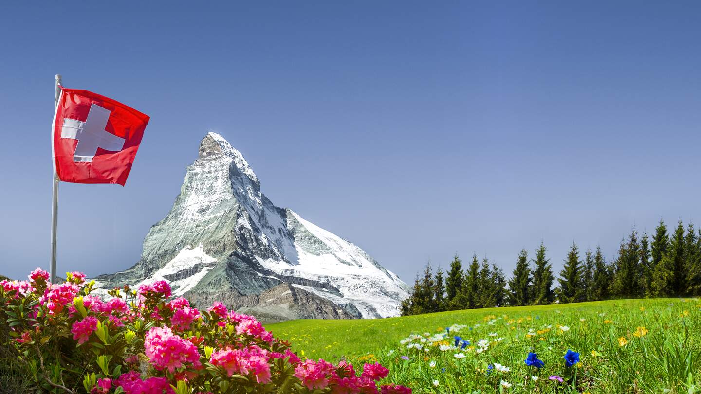 Schweizer Flagge mit Matterhorn und Bergwiese | © gettyimages.com/by-studio