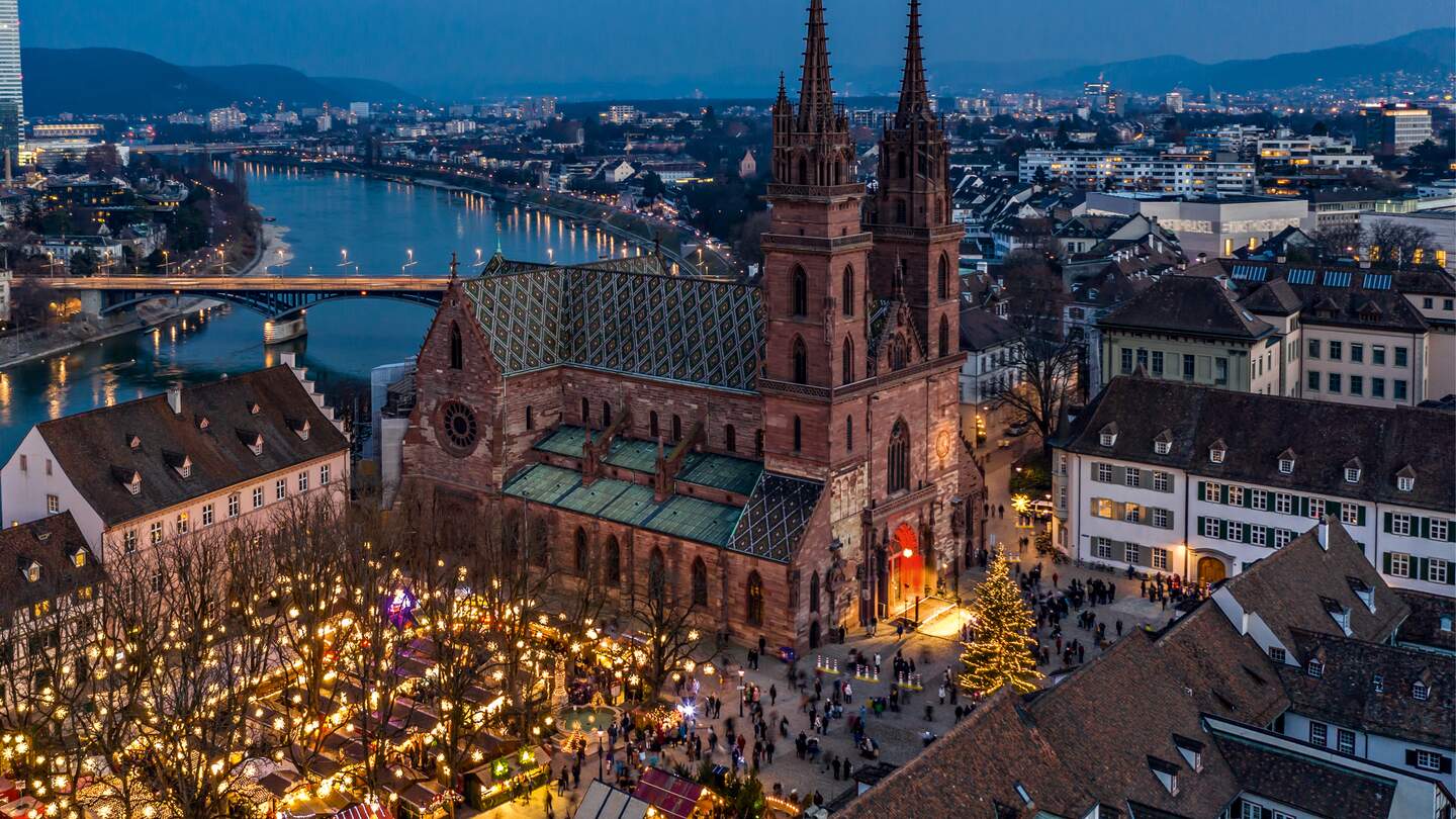 Winterlicher Weihnachtsmarkt mit beleuchtetem Dom und Fluss im Hintergrund | © Schwitzerland Tourismus/Jan Geerk