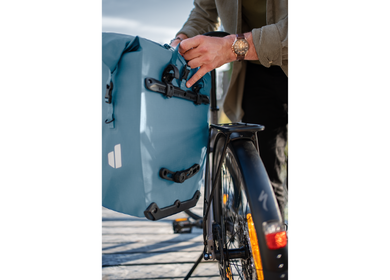 Ein Mann befestigt seine deuter Fahrradtasche "Visby" an seinem Fahrrad, Bild mit weißem Rahmen | © Johannes Bitter/deuter