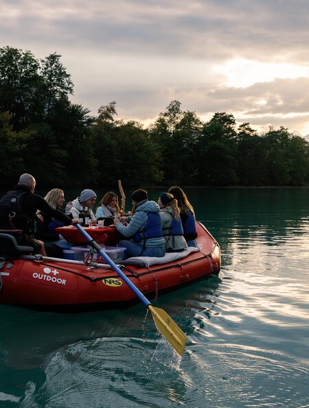 Raclette Rafting | © Outdoor.ch Personen sitzen auf einem Raft im Winter auf einem See und essen Raclette. | © Outdoor.ch