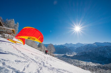 Paragliding im Schnee | © Mike Kaufmann Person beim Paragliding im Schnee mit Sonne | © Mike Kaufmann