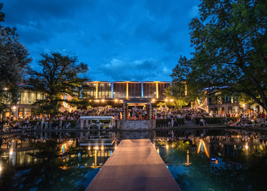 Bild der Konzertnacht 2024 beim Weimarer Sommer. Ein FreiluftTheater mit vielen Menschen. Ein Steg über Wasser führt von der Bühne zu den Zuschauern. | ©  Andre Mey, weimar GmbH