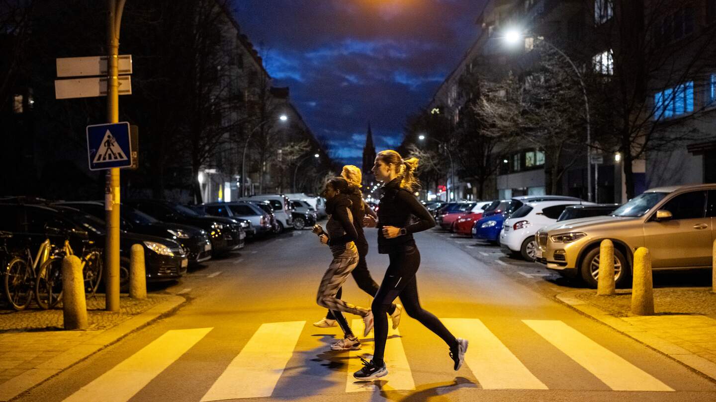 Drei Menschen joggen über einen Zebrastreifen. Es ist Nacht. | © Gettyimages.com/alvarez