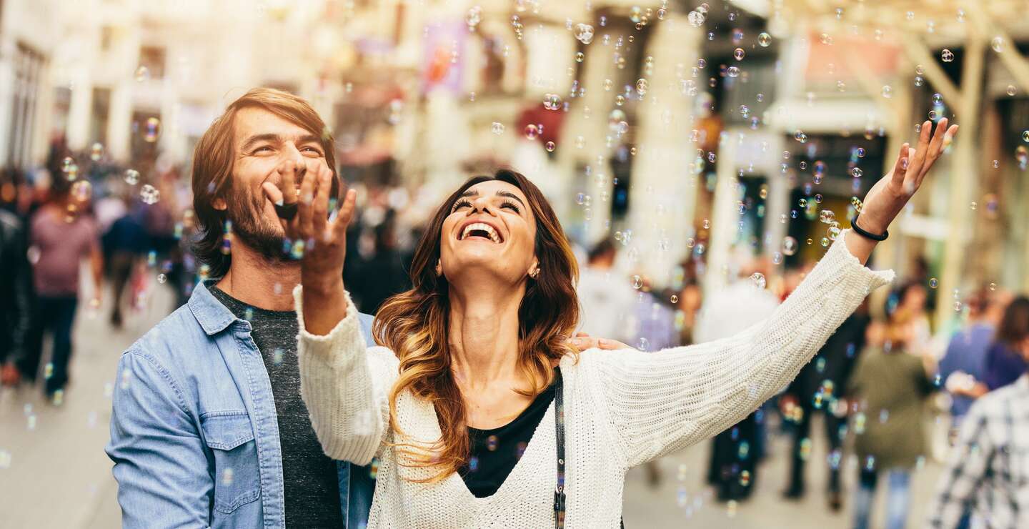 Glückliches junges Paar freut sich an Luftblasen | © Gettyimages.com/filadendron