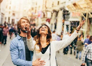 Glückliches junges Paar freut sich an Luftblasen | © Gettyimages.com/filadendron