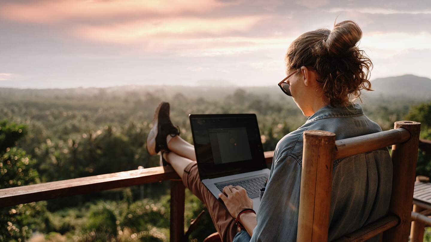 Frau mit Laptop auf einem Balkon | © © Gettyimages.com/Olezzo