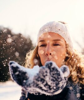 Erwachsene Frau, im Winter draussen, Schnee pustend | © © Gettyimages.com/vgajic
