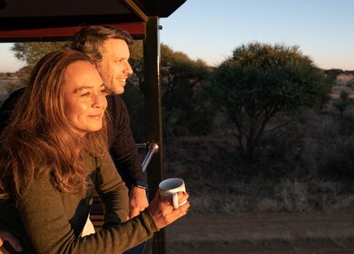 Ein Paar steht während des Sonnenunterganges auf dem Balkon des Rovos Rails in Afrika  | © © Greg Beadle 