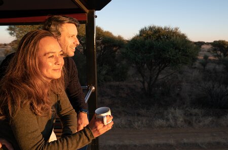 Ein Paar steht während des Sonnenunterganges auf dem Balkon des Rovos Rails in Afrika  | © © Greg Beadle 