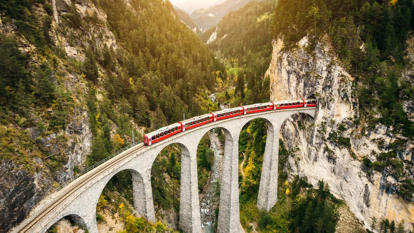 Im Panoramawagen des Bernina Expresses auf dem Landwasserviadukt im Herbst in der Schweiz | © Gettyimages.com/nikada