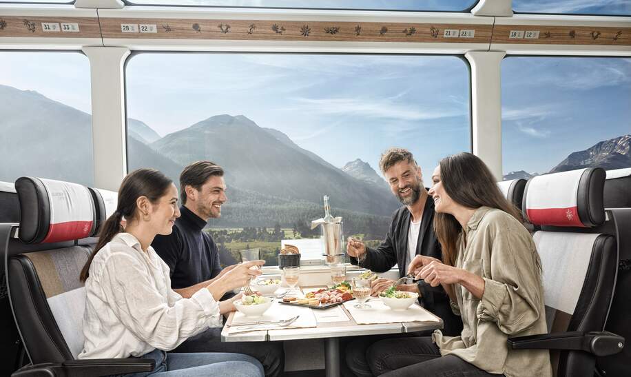 Zwei Paare sitzten im Speisewagen 2. Klasse mit Panoramafenstern | © Glacier Express AG/Stefan Schlimpf