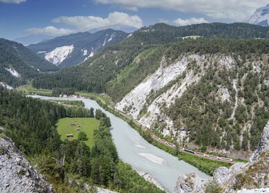 Der Glacier Express der RhB durch die Rheinschlucht auf dem Weg nach Disentis am Ufer des Jungen Rheins entlang | © Gettyimages.com/KvdB50