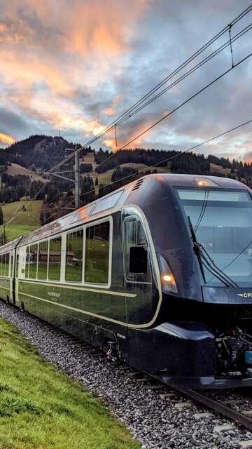 Der Golden Pass Express fährt vor der Kulisse einer grünen Landschaft bei Sonnenuntergang | © MOB - GoldenPass