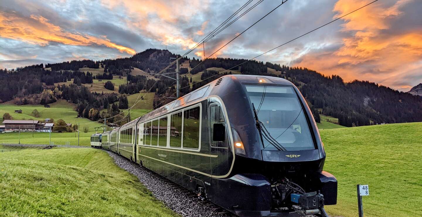Der Golden Pass Express fährt vor der Kulisse einer grünen Landschaft bei Sonnenuntergang | © MOB - GoldenPass