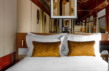 Blick auf ein Doppelbett mit frisch bezogenener Garnitur und zwei Kissen in einer Suite des La Dolce Vita Orient Express | © Orient Express SAS
