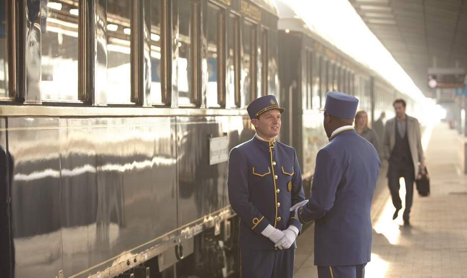 Stewards stehen auf dem Bahnsteig vor dem Venice Simplon Orient Express. Passagiere laufen vorbei. | © © Matt Hind