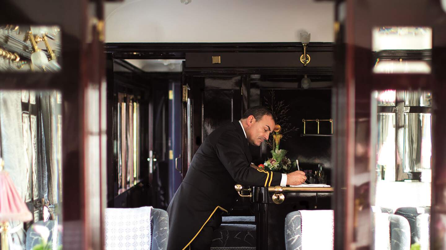 das Innere eines Orient-Express-Waggons, am Ende des Waggons ist ein Schaffner zu sehen  | © gettyimages.com/Neues Thema Helen Cathcart