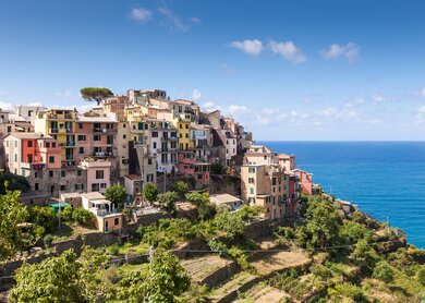 Corniglia ist ein Weiler in der Gegend von Vernazza in der Provinz La Spezia, Ligurien. Im Gegensatz zu den anderen Orten der Cinque Terre liegt Corniglia nicht direkt am Meer. Stattdessen befindet es sich auf der Spitze eines Vorgebirges, das auf drei Seiten von Weinbergen und Terrassen umgeben ist, die vierte Seite fällt steil zum Meer ab. Um Corniglia zu erreichen, ist es notwendig, die Lardarina zu erklimmen, eine lange gemauerte Treppe die vom Bahnhof zum Dorf führt. | © Gettyimages.com/Sam Valtenbergs