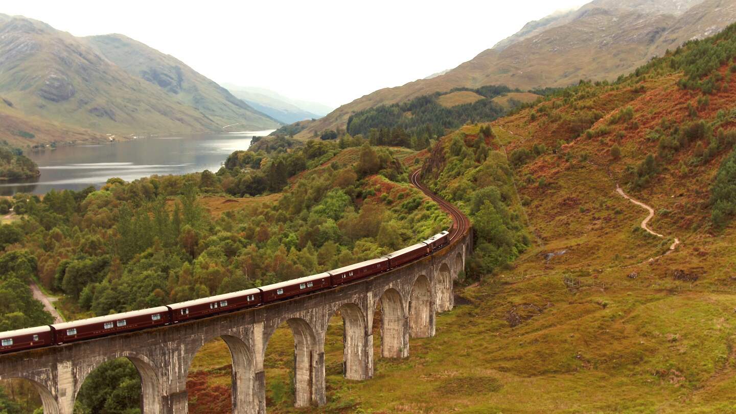 Der Royal Scotsman fährt über ein Viadukt in einem grünen Tal | © belmond.com/Jonangelo Molinari