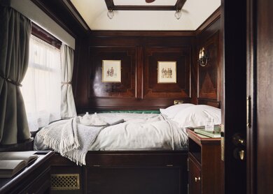Innenraum des Doppelabteils mit einem Bett mit weißer Bettwäsche, einem Tisch und einem Nachttisch | © belmond.com/Ludovic Balay